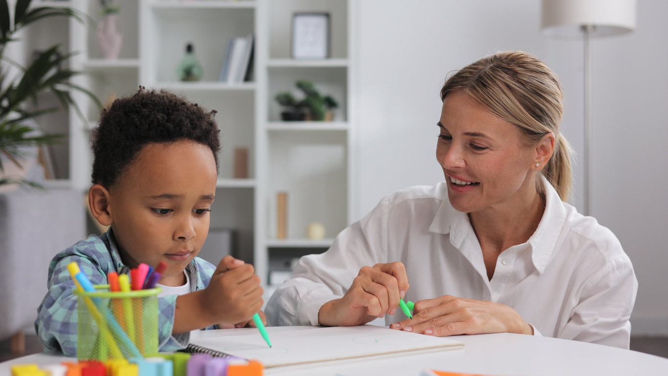 little boy drawing next to an autism testing therapist