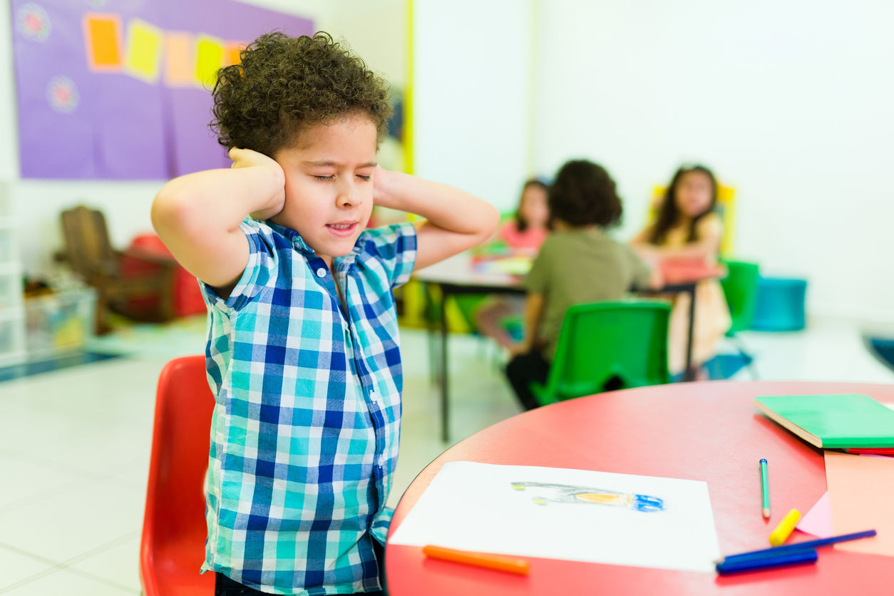 A boy covers his ears with his hands