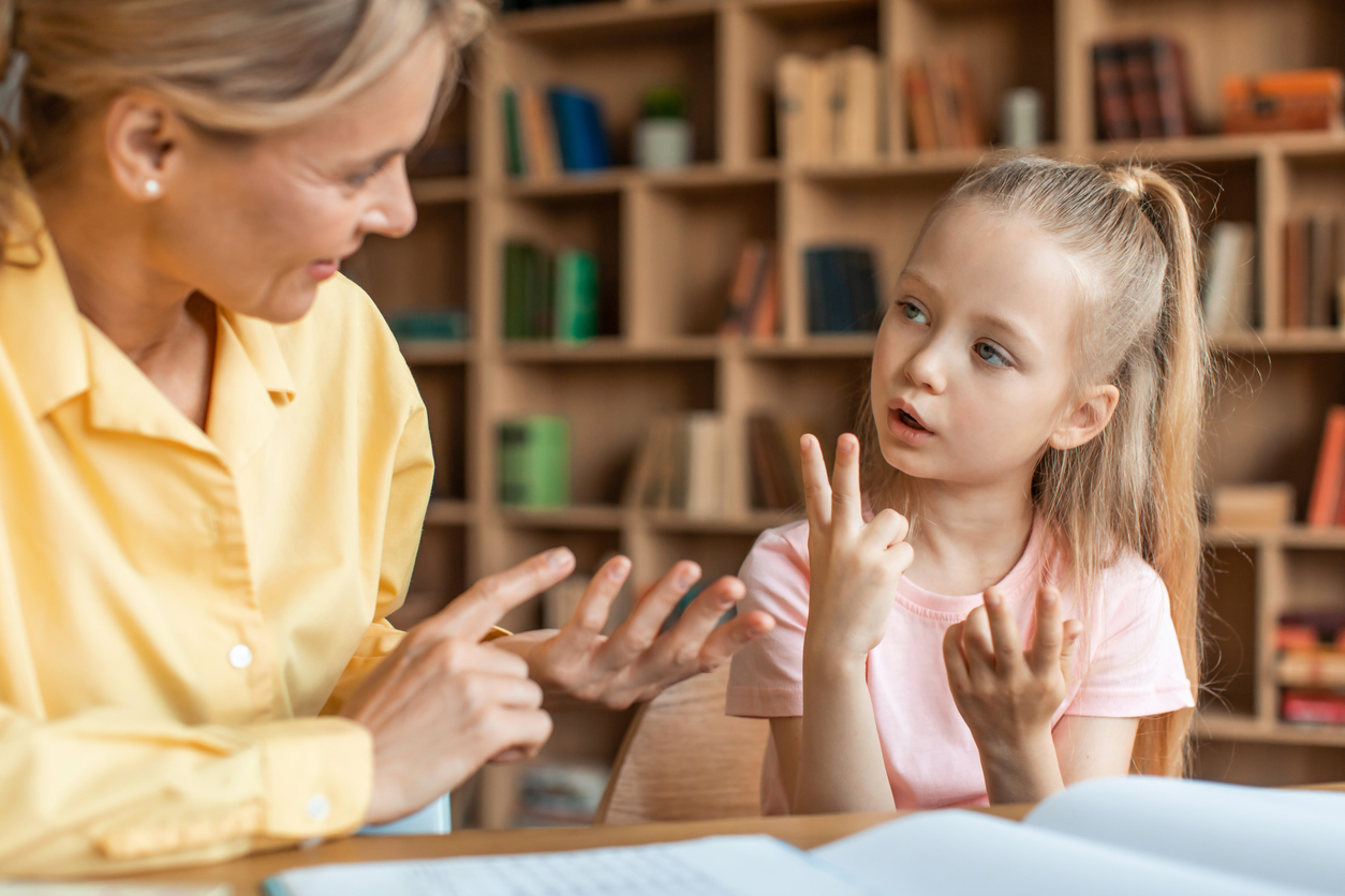 Functional communication therapist and a young girl counting numbers with their fingers.